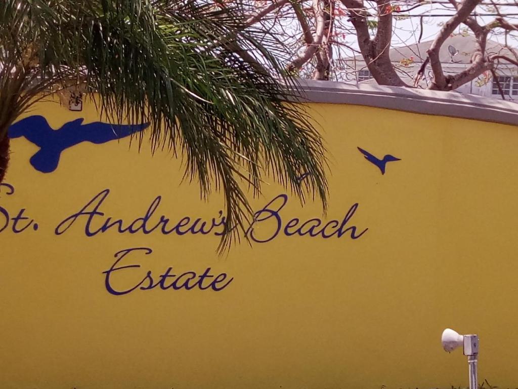 a yellow wall with a sign with birds on it at Personal Touch 1 in Nassau