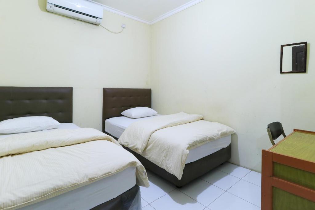 1 Schlafzimmer mit 2 Betten und einem Schreibtisch in der Unterkunft Guest House Samarinda in Samarinda