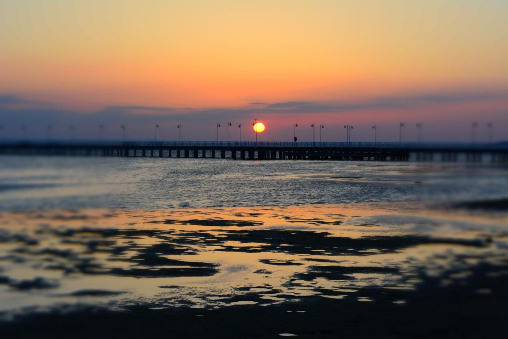 a sunset over a pier with the sun in the background at Floryda Jurata in Jurata