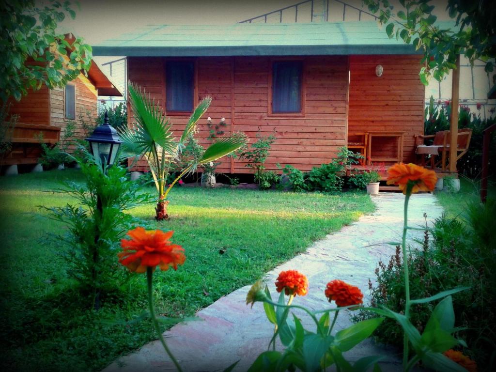 una casa con jardín con flores naranjas en el patio en Sera Pansiyon, en Cıralı