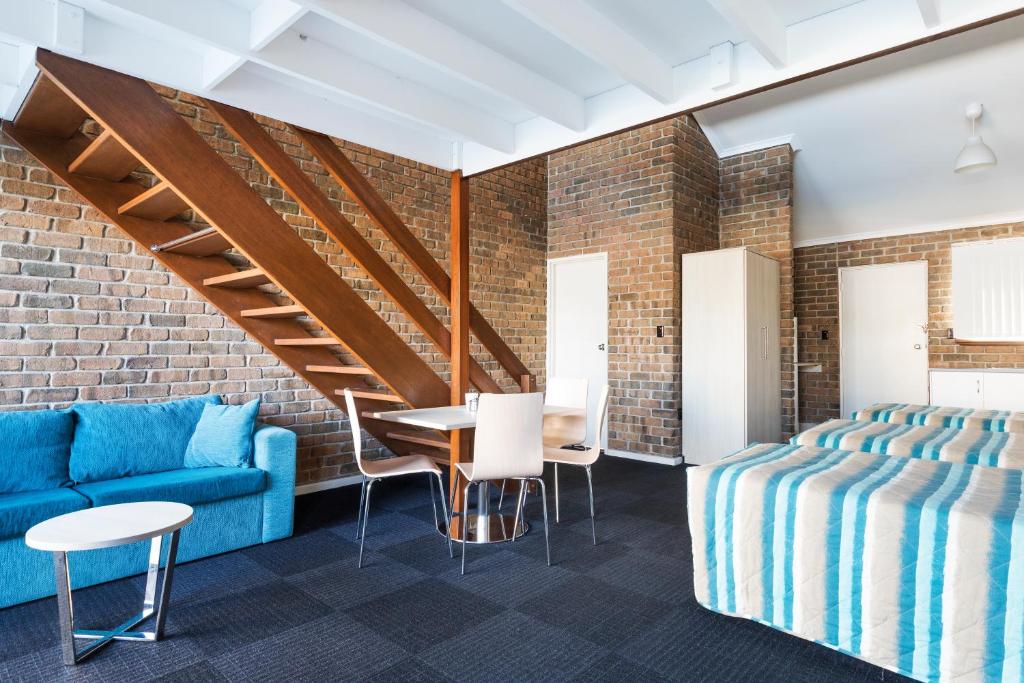 Cette chambre comprend un canapé bleu, une table et des chaises. dans l'établissement Marion Motel and Apartments, à Adélaïde