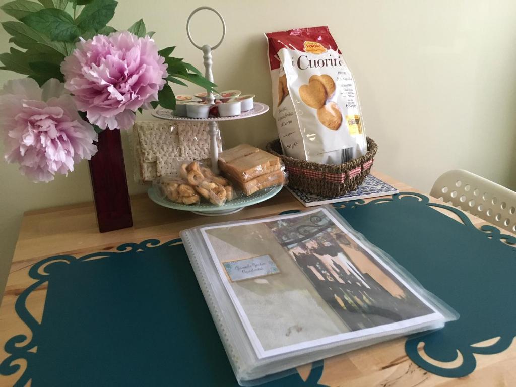 una mesa con un libro y unas galletas y flores en Gianicolo Penny's Garden a Roma centro, en Roma