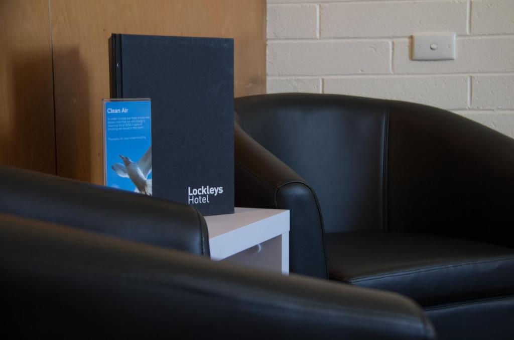 a black chair and a book sitting next to a chair at Lockleys Hotel in Adelaide