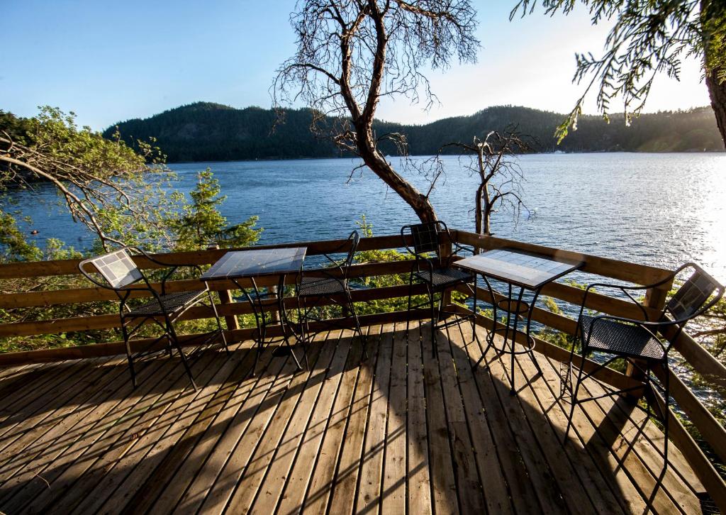 un banco sentado en una terraza junto a un lago en shangrila waterfront vacation home, en Pender Island