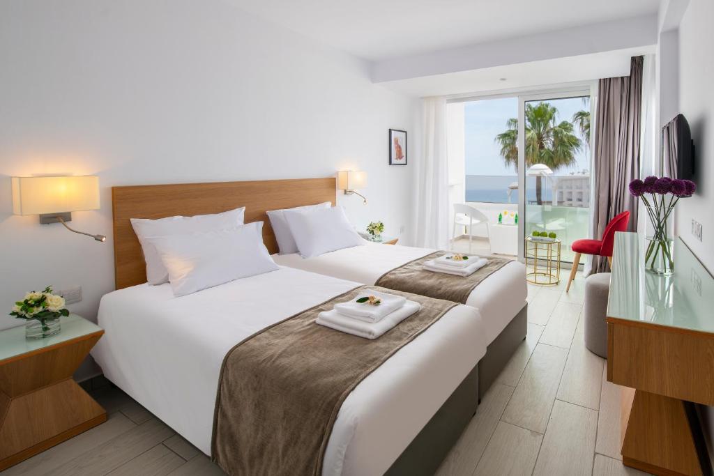 a hotel room with two beds and a view of the ocean at Kokkinos Boutique Hotel in Protaras