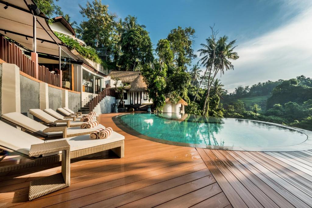 un complexe avec une piscine et des chaises longues dans l'établissement Tanadewa Resort Ubud Bali by Cross Collection, à Ubud