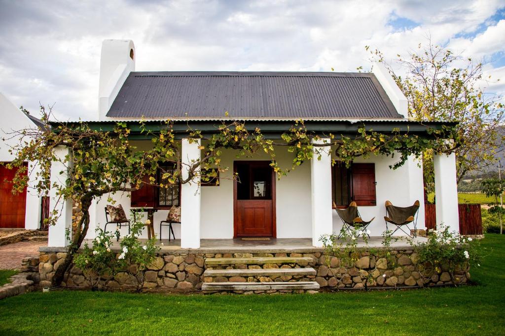 a white house with a stone wall at Vineyard Cottage at Bosman Wines in Wellington