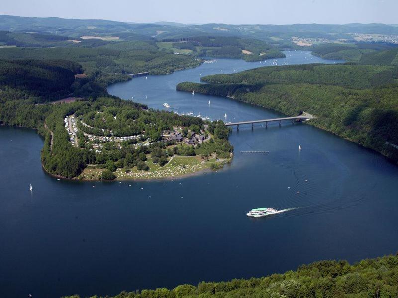 a boat in a large lake with a bridge at Ferienwohnung Olpe Biggesee in Olpe