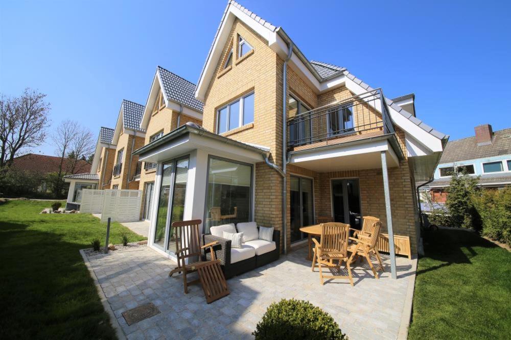 una casa con un patio con mesa y sillas en Ferienhaus Sommerhus 3, en Timmendorfer Strand