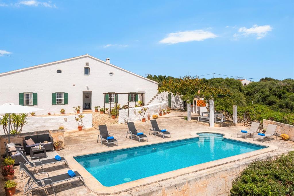 a swimming pool with chairs and a house at Finca Binicalaf Vell in Cala'n Porter