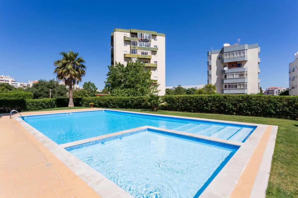 uma piscina com dois edifícios altos ao fundo em Apartamento Tatiana em Portimão