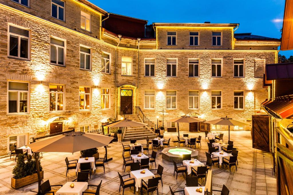 um pátio com mesas e guarda-sóis em frente a um edifício em The von Stackelberg Hotel Tallinn em Talin