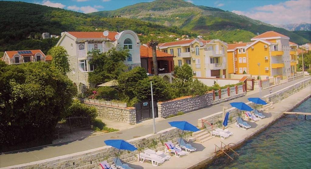 a group of chairs and blue umbrellas next to the water at Vila La ViTa del Mare in Bijela