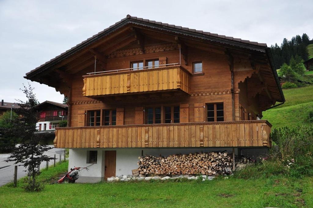 a wooden house with a pile of fire wood at Ferienwohnungen Hotel Alpina in Adelboden