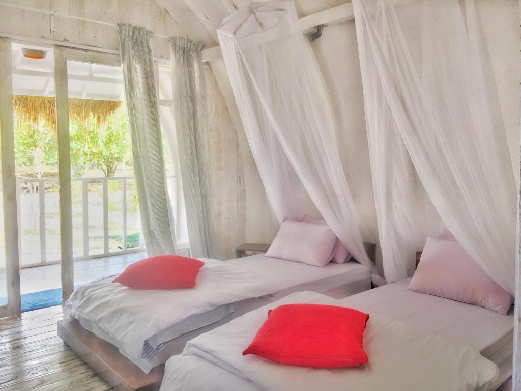 Duas camas com almofadas vermelhas num quarto com uma janela em Maleo Moyo Hotel & Dive Resort em Moyo Island