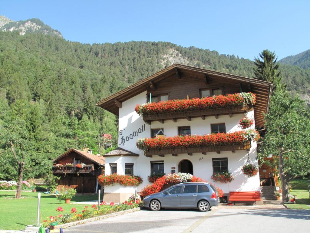 a car parked in front of a building with flowers at sHoamatl in Pfunds