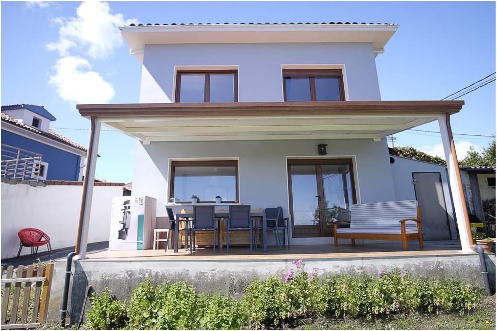 Cette maison blanche dispose d'une terrasse couverte avec une table et des chaises. dans l'établissement Aldea de Ribadesella, à Sardalla