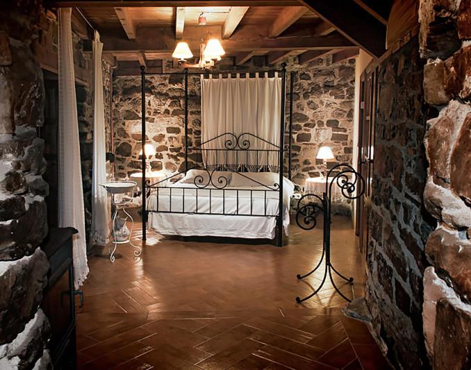1 dormitorio con 1 cama en una pared de piedra en Casa de Ligueria en Rozapanera