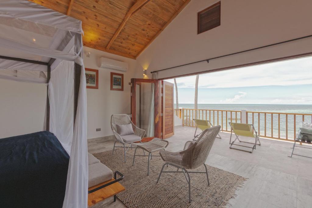 ein Schlafzimmer mit einem Bett und Stühlen auf einem Balkon in der Unterkunft Asali Beach House in Jambiani