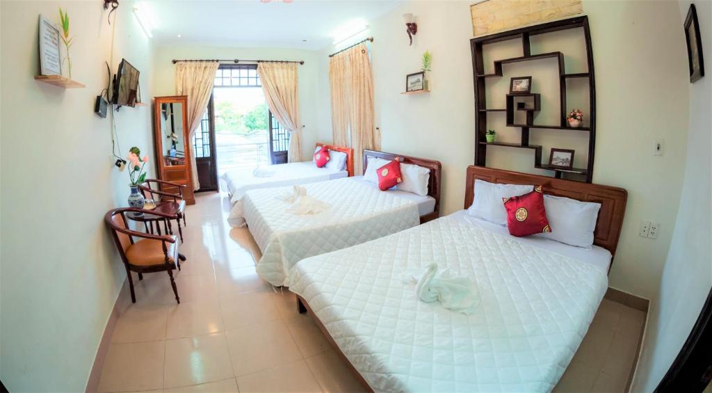 um quarto de hotel com duas camas e um corredor em Rubis Hostel em Hue