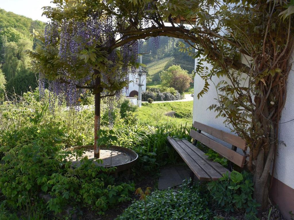 un banco en un jardín con un árbol y flores en Ferienwohnung Wiedergrün, en Durbach