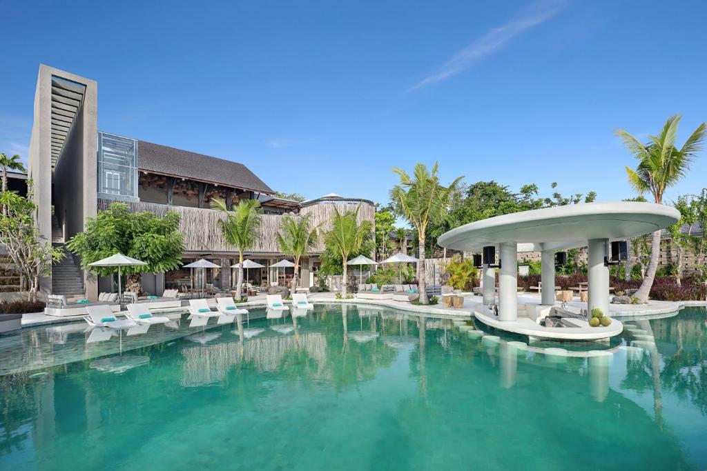 a pool at a resort with chairs and umbrellas at Cross Bali Breakers - formerly X2 Bali Breakers in Jimbaran