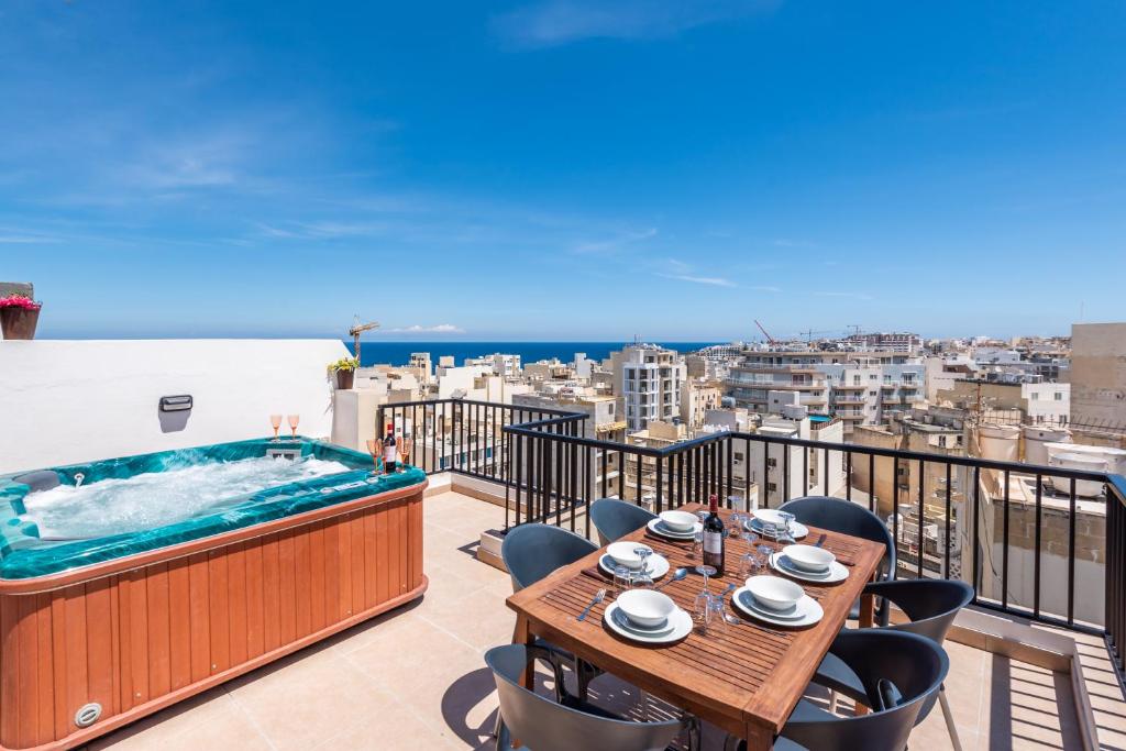 balcón con bañera de hidromasaje, mesa y sillas en Seashells Sea View Penthouse with private Hot Tub & large sunny terrace with stunning views - by Getwaysmalta en St. Paul's Bay