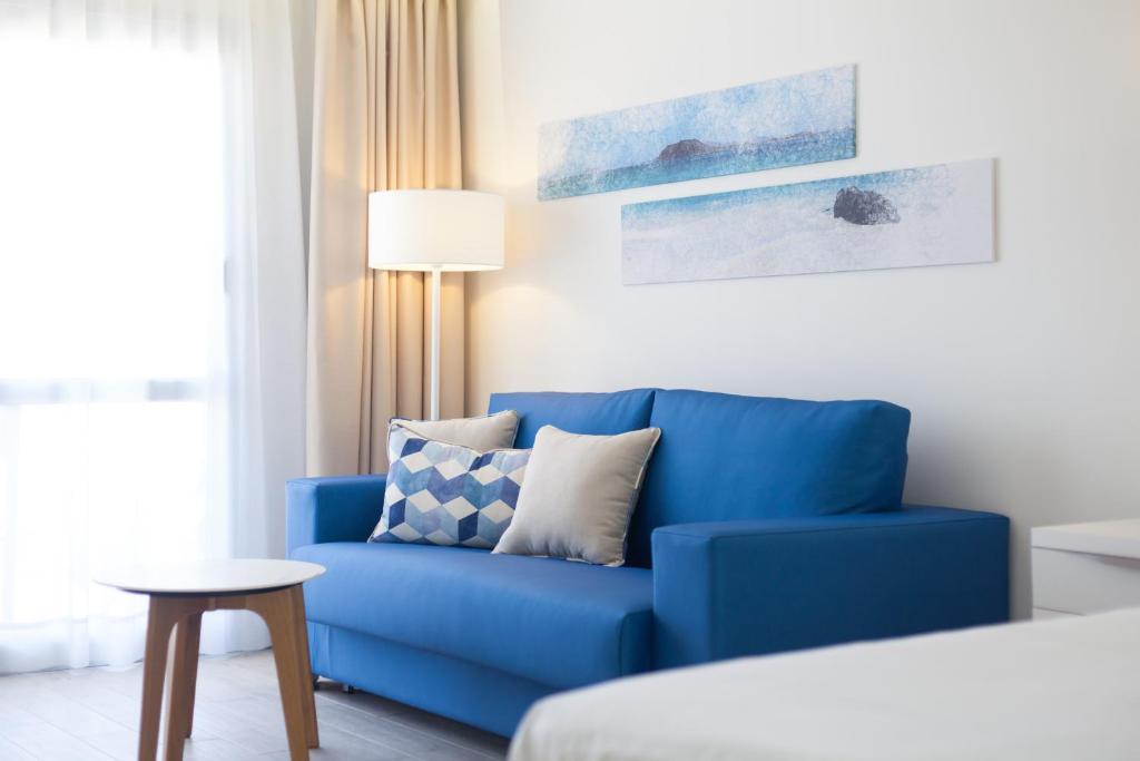 a blue couch in a room with a bed at Hotel Boutique TAO Caleta Mar in Corralejo