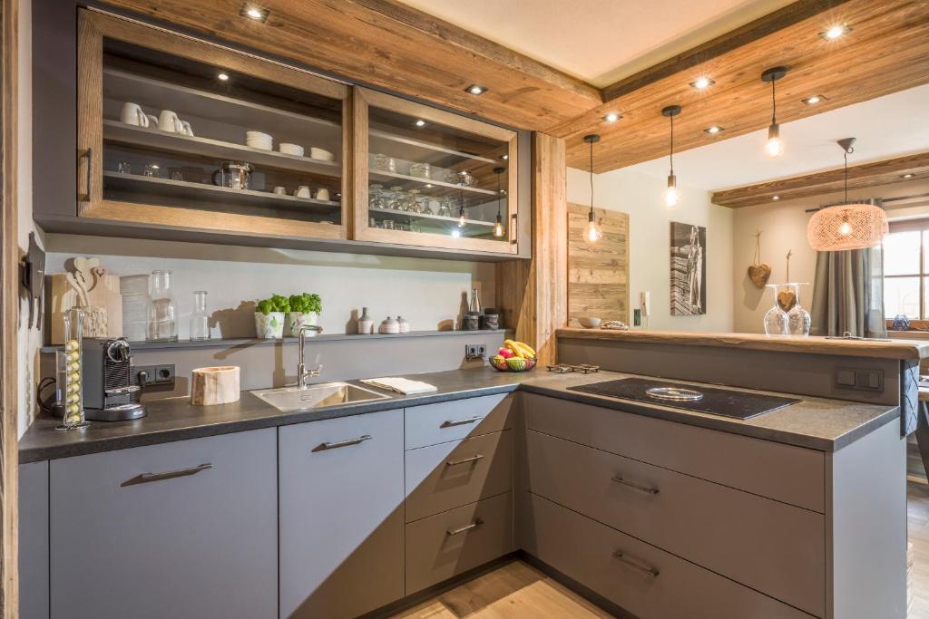 una cocina con armarios blancos y techos de madera. en Apartment Enzian en Ellmau