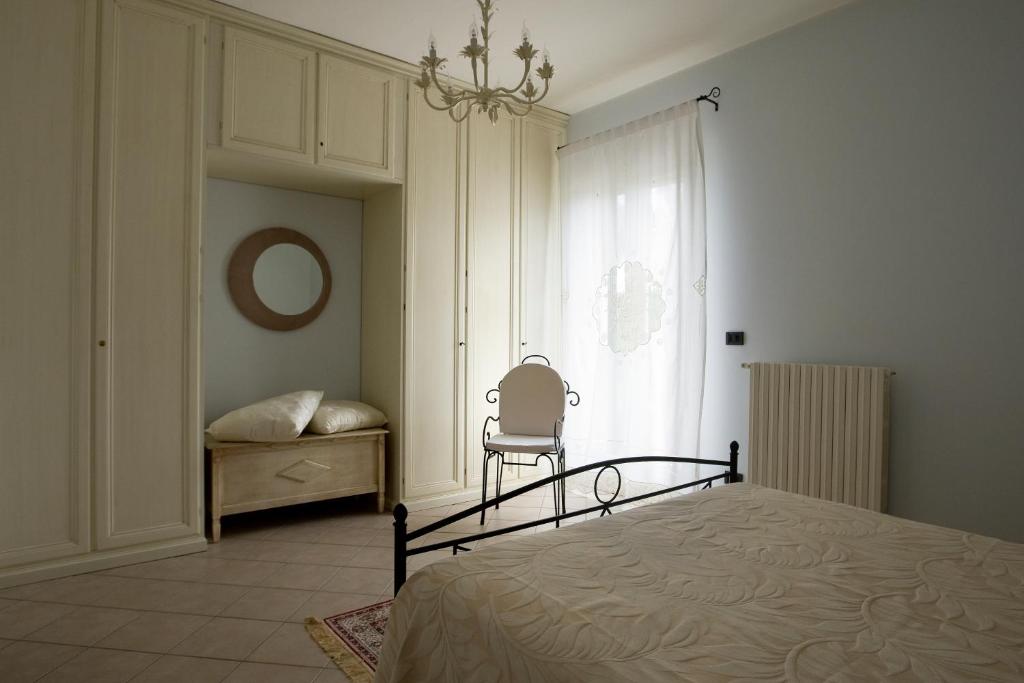ein Schlafzimmer mit einem Bett, einem Stuhl und einem Fenster in der Unterkunft Il Giardino Delle Sete in Mesagne