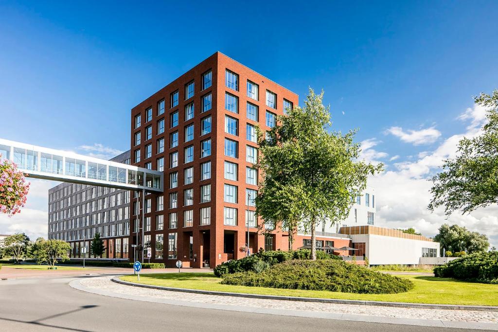 een rood bakstenen gebouw met een boom ervoor bij Fletcher Wellness-Hotel Helmond in Helmond