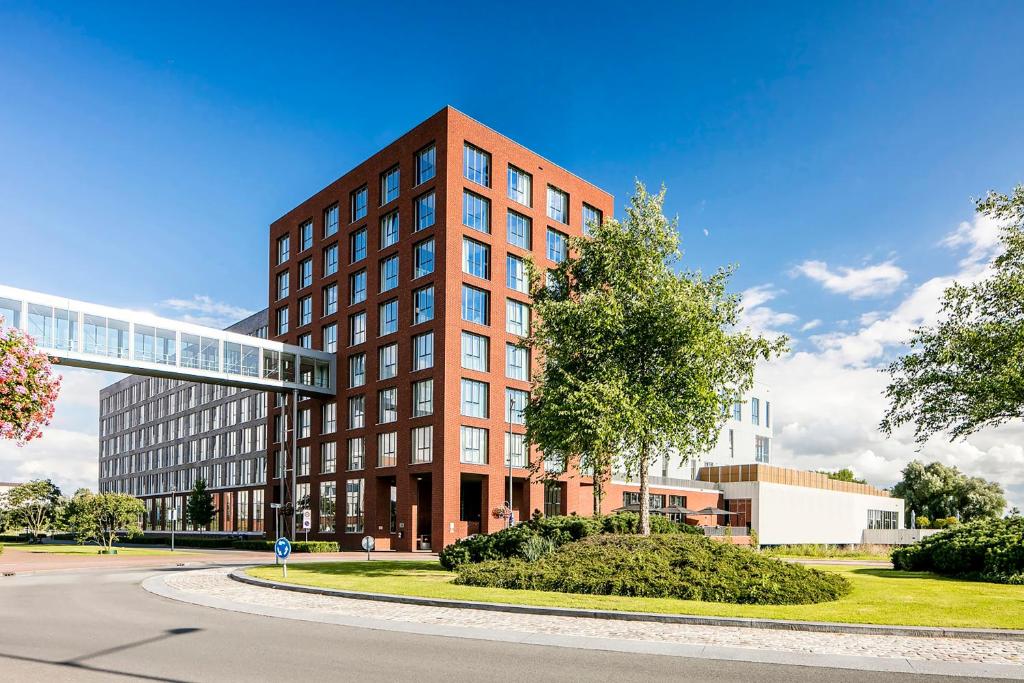 ein rotes Backsteingebäude mit einem Baum davor in der Unterkunft Fletcher Wellness-Hotel Helmond in Helmond