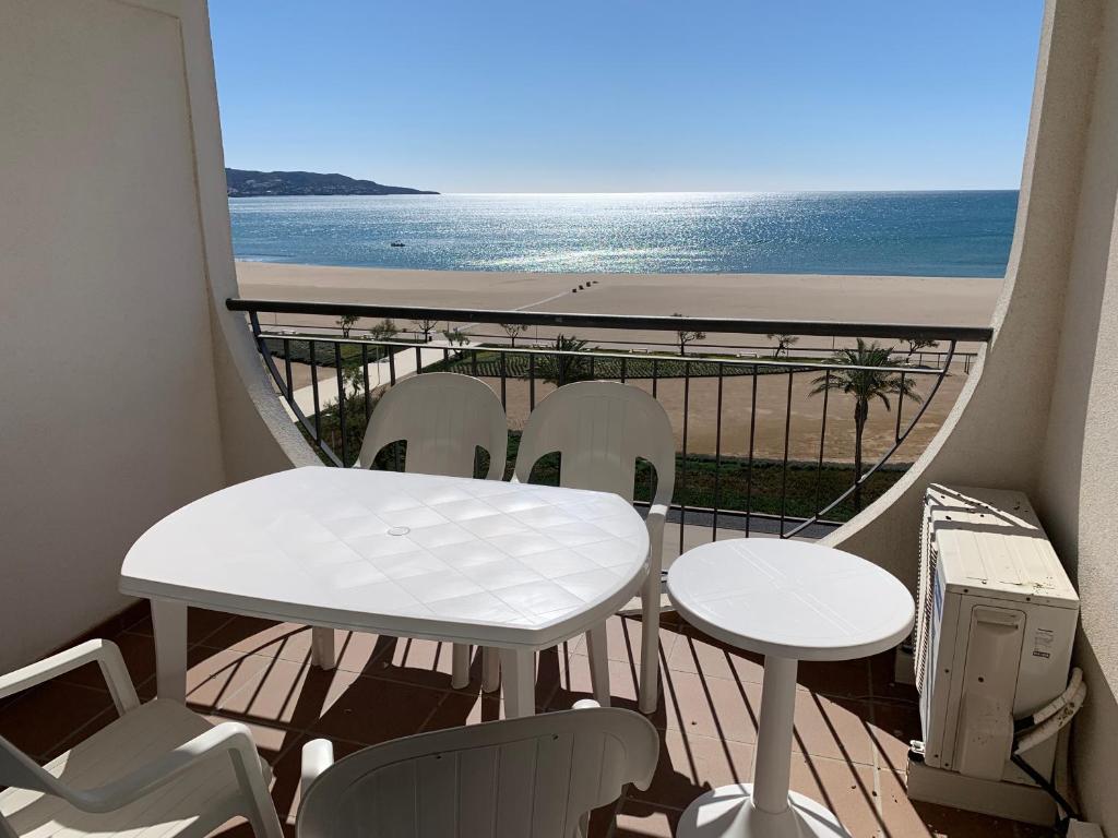 een balkon met een tafel en stoelen en de oceaan bij AwayDays - 94 - Appartement 1 Chambre Vue Mer in Empuriabrava