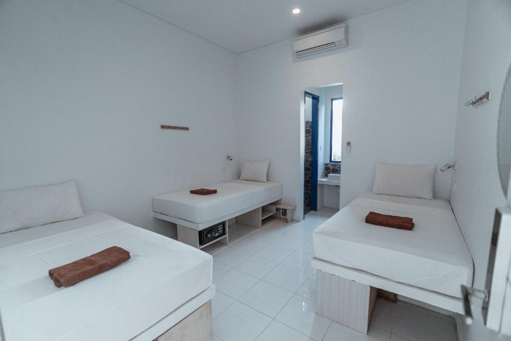 Habitación blanca con 2 camas y lavamanos en Atlas Gili, en Gili Trawangan