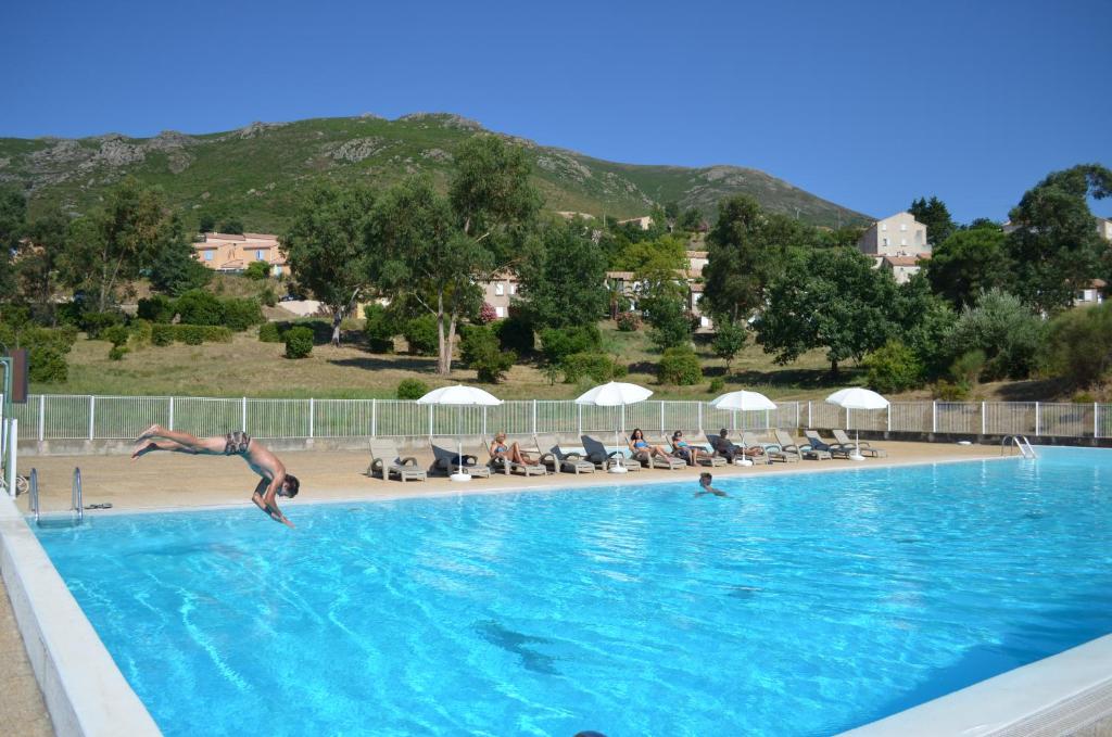 Un homme sautant dans une piscine dans l'établissement Hôtel "U Nebbiu", à Oletta