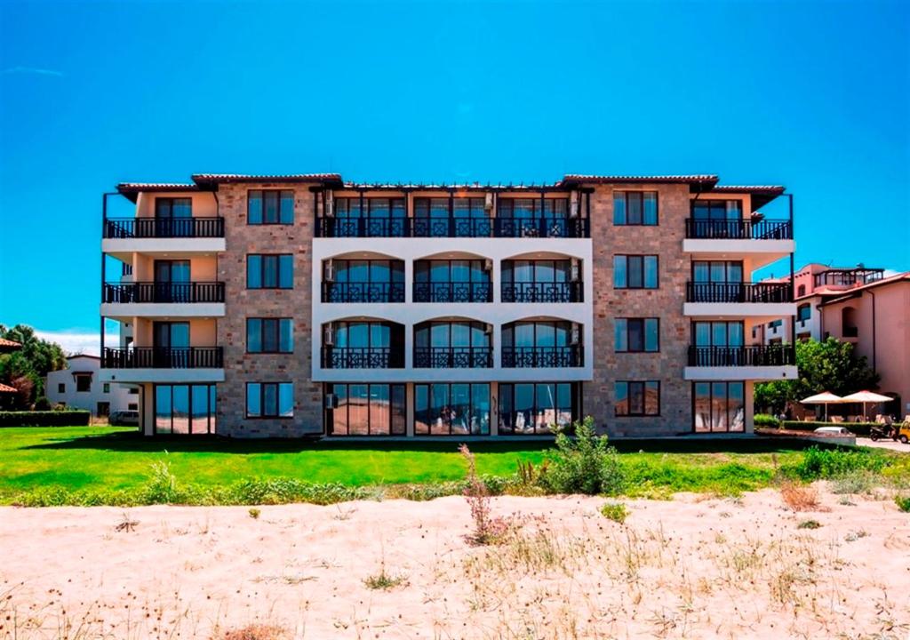 an apartment building on the beach with the sand at Oasis Del Sol - Front Beach in Lozenets