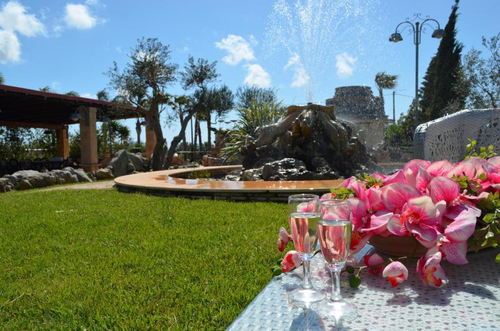 uma mesa com copos de vinho e flores cor-de-rosa em Masseria Grande em Taurisano