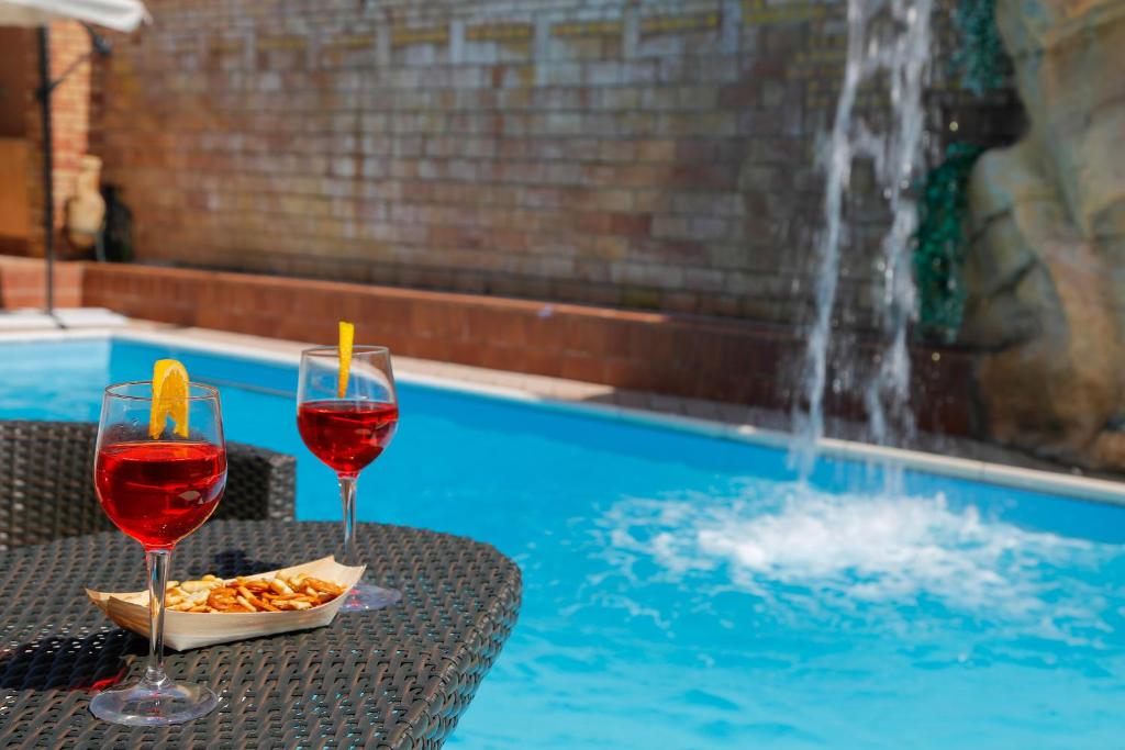 アグローポリにあるB&B Villa Mariaのスイミングプールの隣のテーブルに座ったワイン2杯