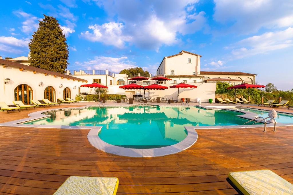 una piscina en un complejo con sombrillas rojas en Villa Tolomei Hotel & Resort, en Florencia