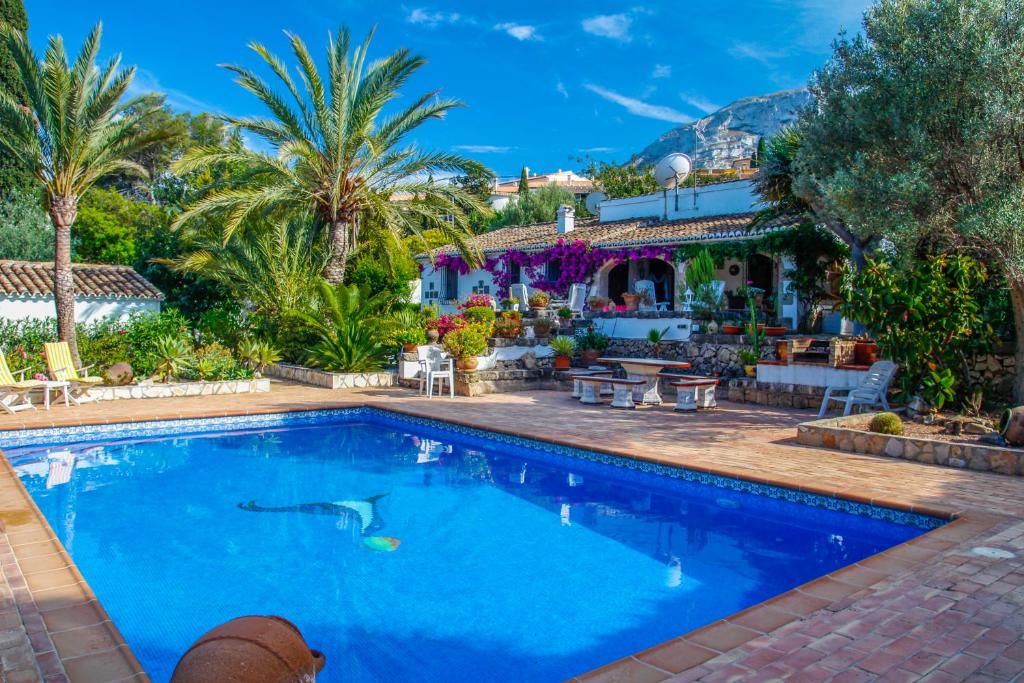 una piscina di fronte a una casa con palme di Villa Quinta a Denia