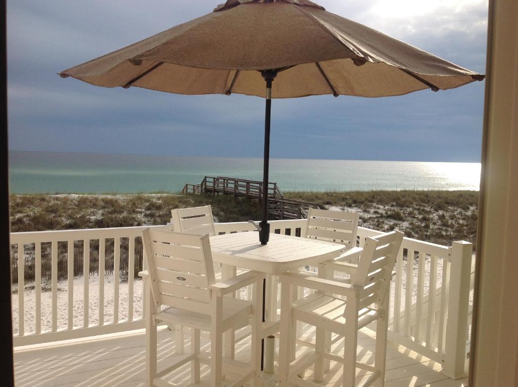 a table and chairs on a balcony with an umbrella at Life's A Beach Townhouse in Navarre