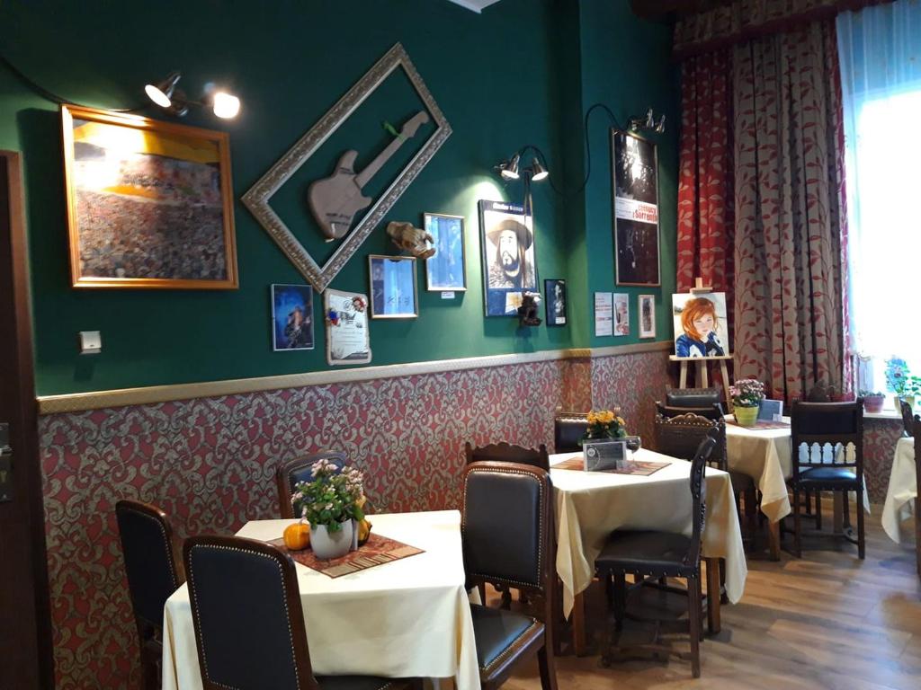 een eetkamer met tafels en stoelen en groene muren bij Willa Sorrento in Szczecin
