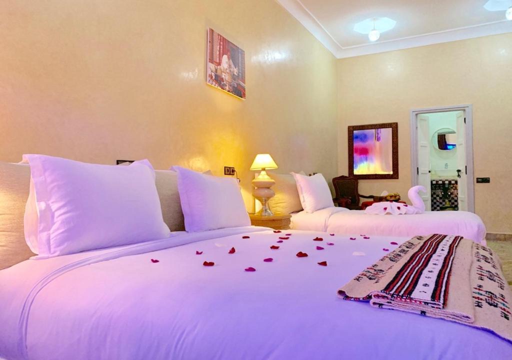 Dos camas en una habitación de hotel con rosas en la cama en KOUTOBIA ROYAL en Marrakech