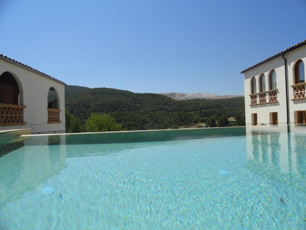 a large pool of blue water in front of a building at Ca l' Ermitanyo- Casa Torre Blanca in Suria