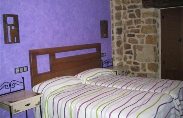 a bedroom with two beds and a stone wall at La Botería in Salas de los Infantes