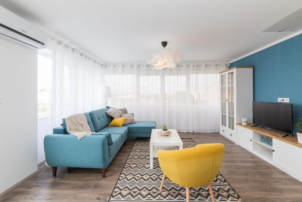 a living room with a blue couch and a yellow chair at Apartmani Zara in Zaton