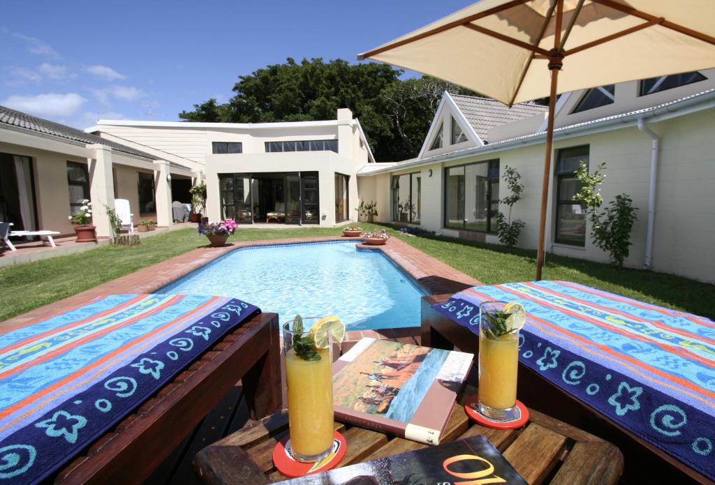 a swimming pool with two tables and an umbrella at Sheilan House in Port Alfred