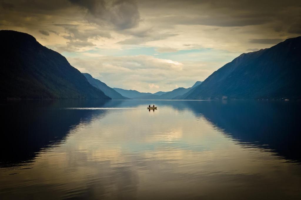 a boat in the middle of a lake with mountains at Sandviken Camping in Austbygdi