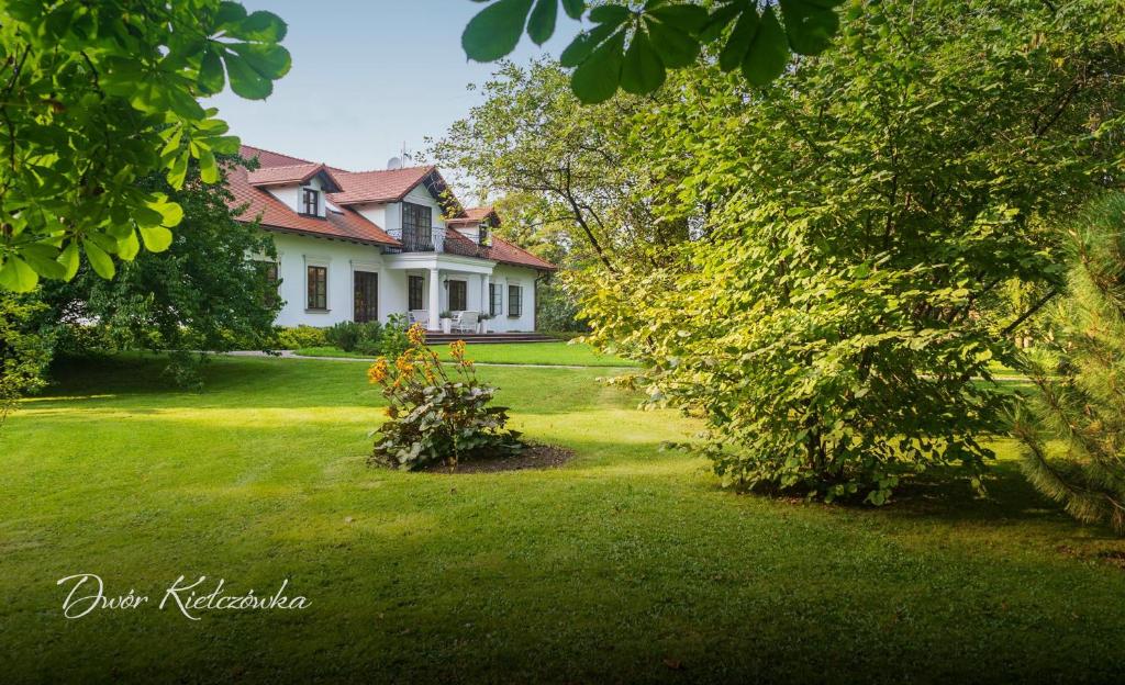 una casa con un cortile con erba verde e alberi di Dwór w Kiełczówce a Moszczenica