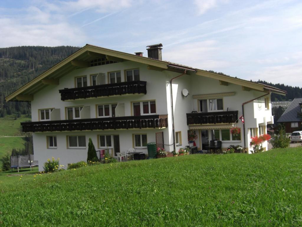 ein Haus auf einem Hügel mit einem grünen Feld in der Unterkunft Gästehaus Boersch in Riezlern